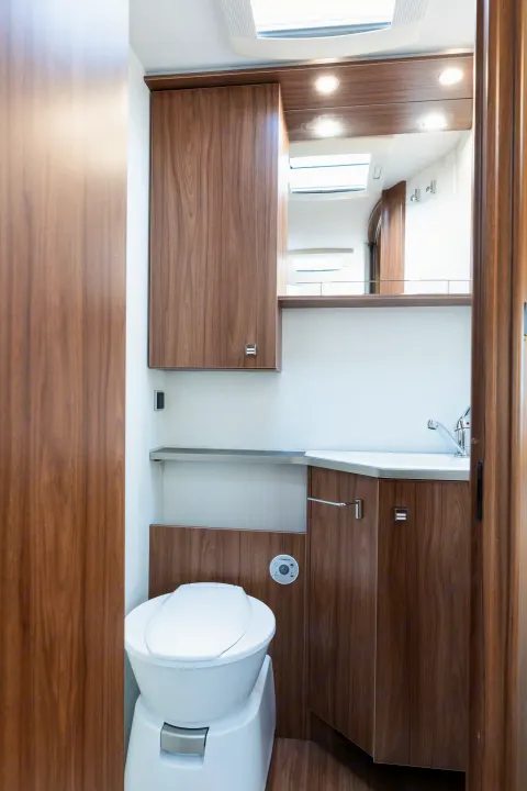 Clean RV rental bathroom featuring a toilet, sink, mirror, and modern wood cabinets.. Pilote P746 A 2025