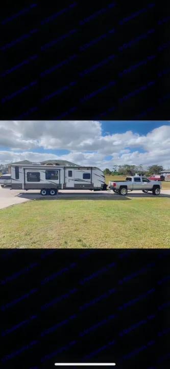 A large Wildwood travel trailer, an RV rental, with extended slide-outs, hitched to a silver pickup truck, parked outside.. Forest River Wildwood 2018