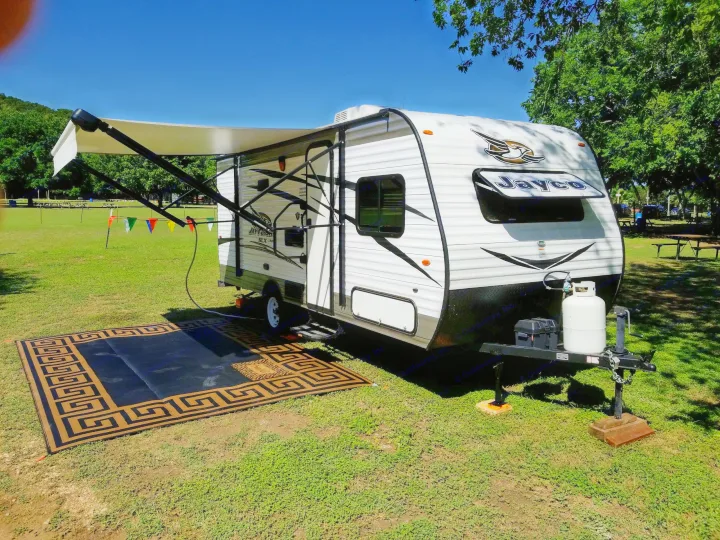 Enjoying the outdoors with this rv rental, featuring an extended awning, propane tank, and a decorative outdoor mat.. Jayco SLX - 21.5' 2017