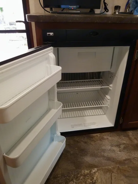Clean, empty refrigerator inside an RV, perfect for your next rv rental adventure. Features shelves & door storage.. Jayco SLX - 21.5' 2017