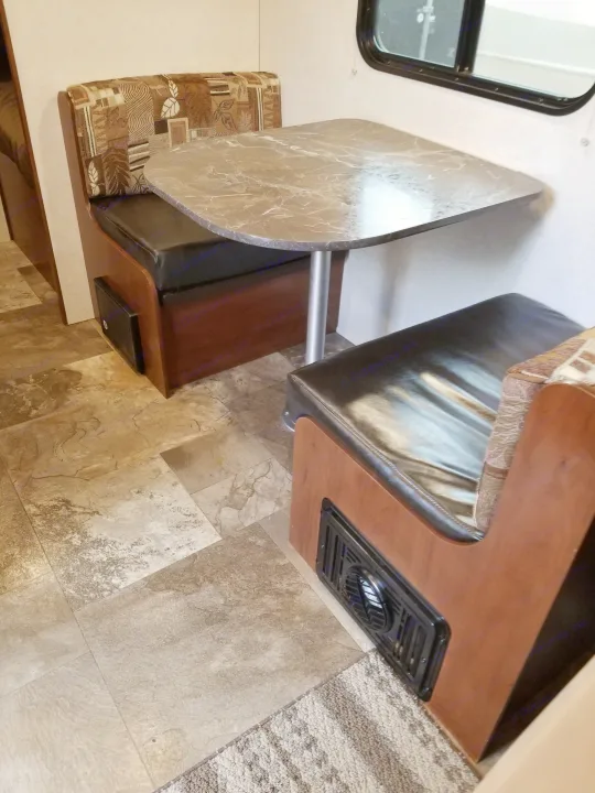 RV rental dinette area: a grey marble-look table, two upholstered benches, and a large window.. Jayco SLX - 21.5' 2017