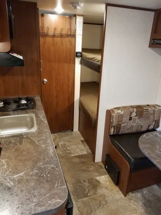 Cozy RV rental interior with dinette, bunk beds, kitchen, and warm wood finishes.. Jayco SLX - 21.5' 2017