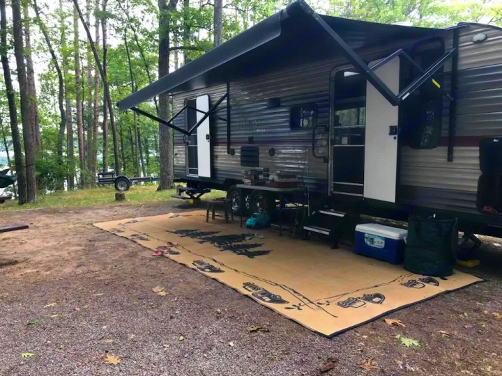 RV rental parked at a peaceful lakeside campsite with an extended awning & outdoor gear.. Forest River Cherokee Grey Wolf 2019
