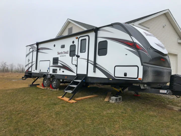 North Trail RV rental: a white travel trailer with black accents, parked on grass and stabilized with blocks.. Heartland North Trail 2019