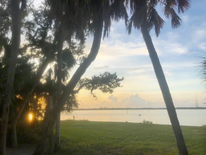 Sunrise over a tranquil bay, framed by silhouetted palms, with kayakers & paddlers. An ideal RV rental destination.. InTech RV InTech RV Trailer 2021