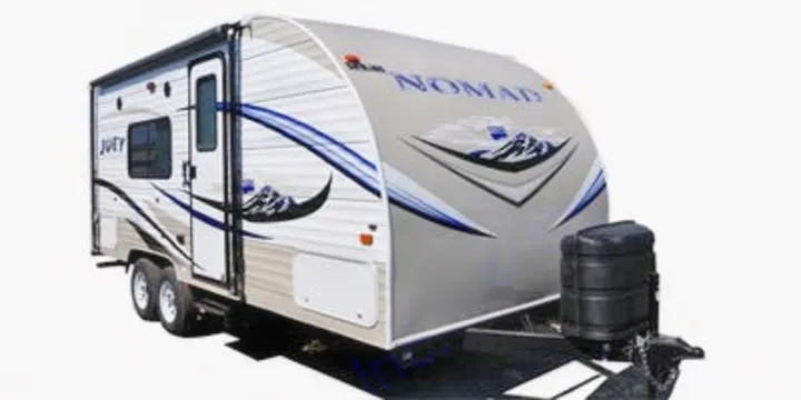 Grey & white Nomad travel trailer RV rental, with blue mountain graphics & 'JOEY' branding on the side.. Skyline Aljo 2015