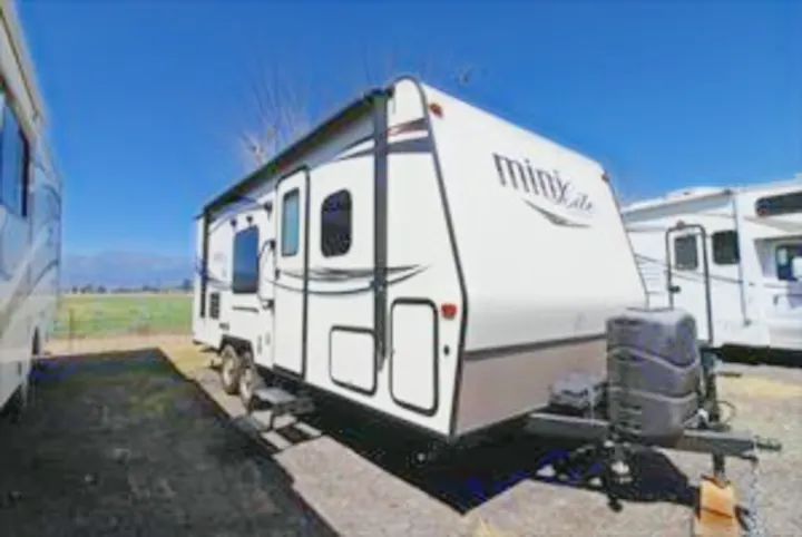 This white travel trailer, 'MINI Lite,' is ready for your RV rental adventure. Parked outdoors.. Forest River Rockwood 2016