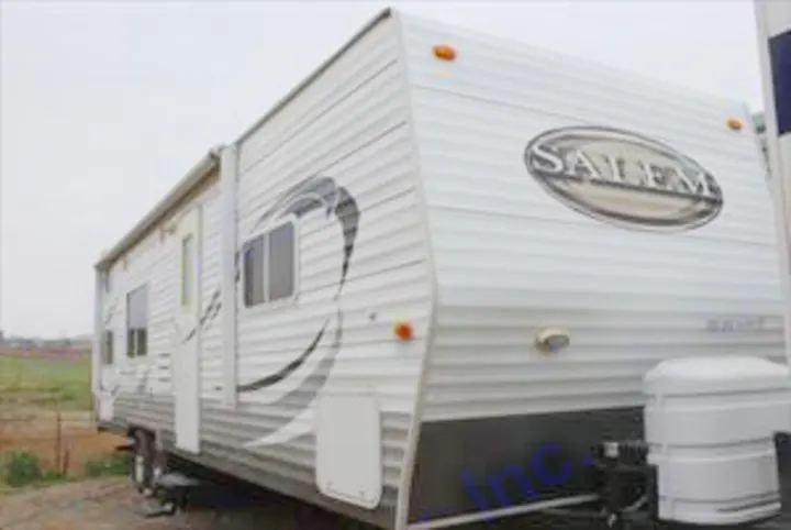 This white Salem travel trailer, ideal for RV rental, features an awning & front propane tanks for outdoor adventures.. Forest River Salem 2010