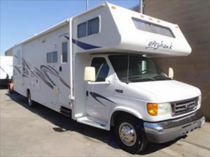 This white Class C RV rental, a Greyhawk motorhome, is ready for travel. It has blue graphics and an extended side for more space.. Jayco Greyhawk 2015