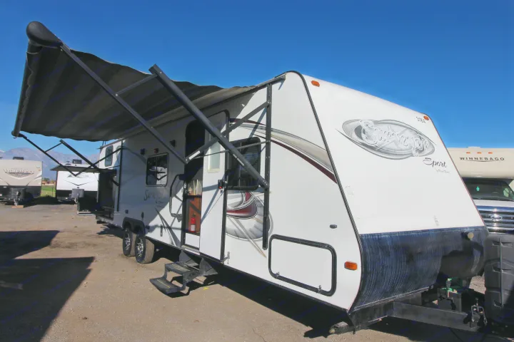 White travel trailer RV with extended awning & steps, parked outdoors. Ideal for your next rv rental adventure.. Forest River Surveyor 2015