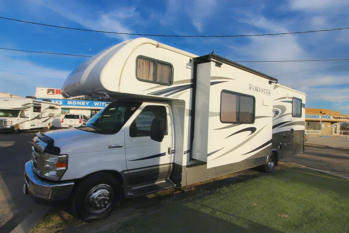 Bright Class C Forest River Forester RV rental with slide-out extended, parked on turf beside a lot.. Forest River Forester 2016