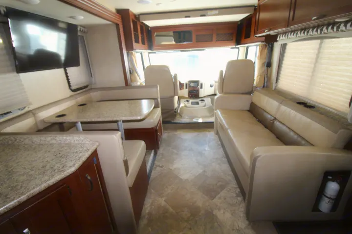 Spacious RV rental interior featuring a dinette, sofa, kitchen counter, and cockpit area.. Thor Motor Coach A.C.E 2016