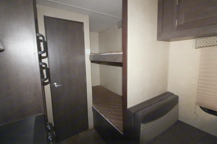 rv rental: Compact RV interior with dark wood bunk beds, a dark door, small seating area, and overhead cabinets.. Forest River Sonoma 2017