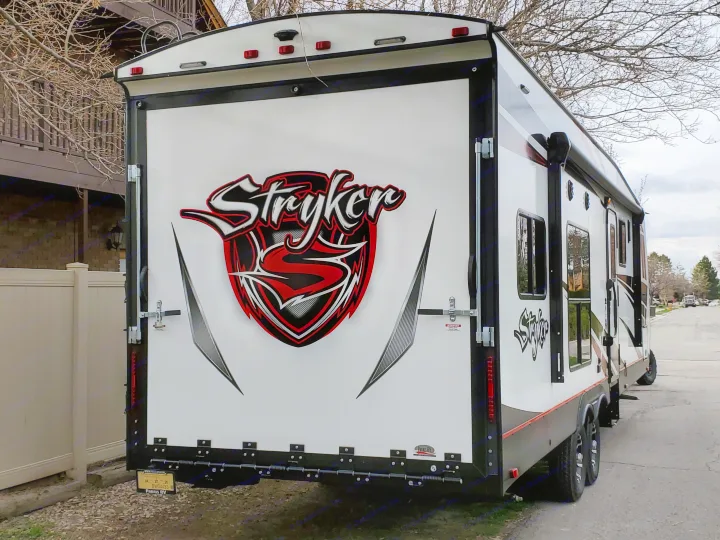 Rear view of a white Stryker toy hauler RV, ideal for an rv rental, featuring its large ramp door & bold branding.. Cruiser Rv Corp Stryker 2020