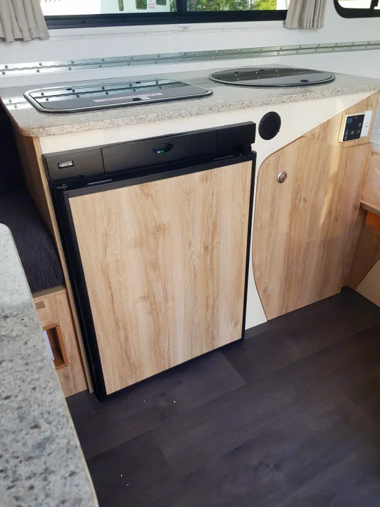 RV rental kitchen with a covered cooktop, sink, and Thetford refrigerator. Control panel also visible. Perfect for road trips!. Avan Aliner Camper 2022