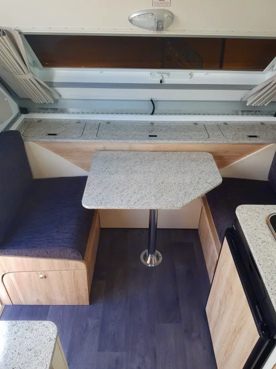 Experience this compact RV rental interior with a cozy dining area, comfy seating, speckled table, and practical counter space.. Avan Aliner Camper 2022