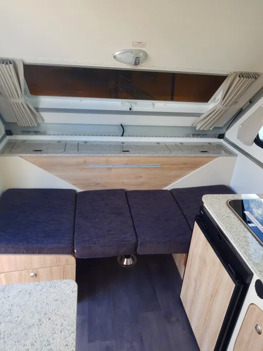 RV rental: Bright camper interior with dark grey convertible seating, kitchen, overhead storage, & wood-look floor.. Avan Aliner Camper 2022