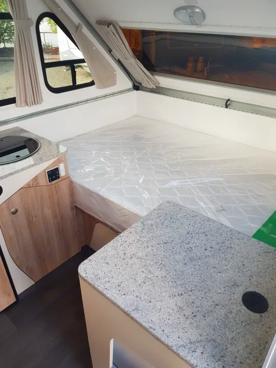 Modern RV rental interior with a comfortable bed, compact kitchenette, and sleek granite-look counters.. Avan Aliner Camper 2022