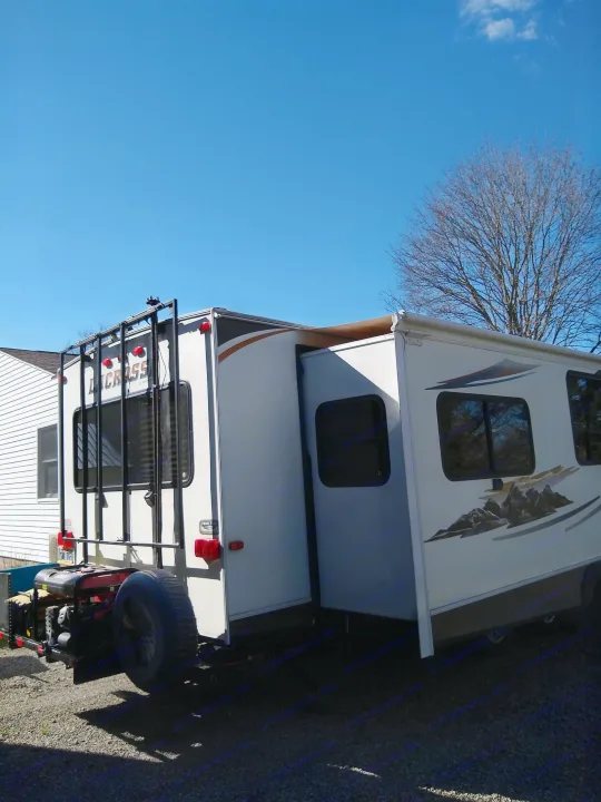 White Lacrosse travel trailer (RV rental) with slide-out extended, parked on gravel under a clear blue sky.. Prime Time Lacrosse 2013