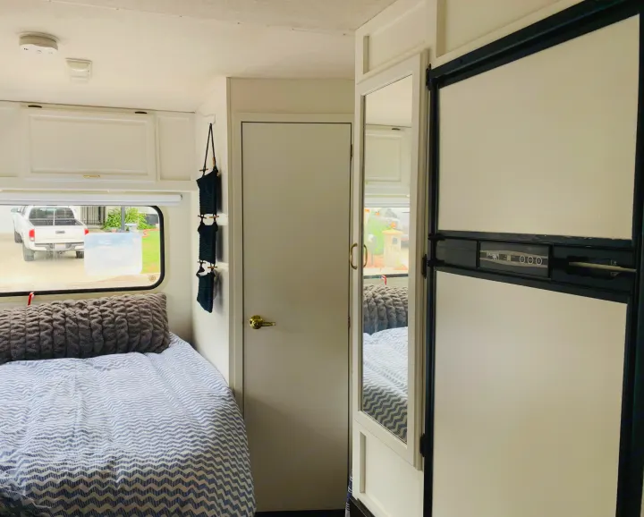 Step inside this cozy RV rental: a modern interior with blue bedding, white cabinets, and a convenient fridge/freezer.. Itasca Spirit 1999