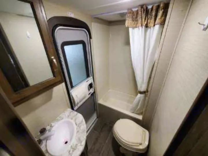 Compact rv rental bathroom with toilet, sink, and shower/tub combo, ensuring comfort during your travels.. Keystone Bullet 2019