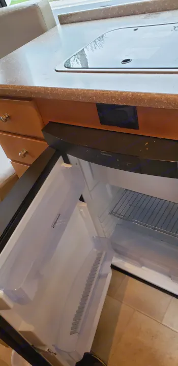RV rental kitchenette featuring a clean, open Dometic refrigerator and sleek countertop with integrated cooktop.. ERA Era 2010