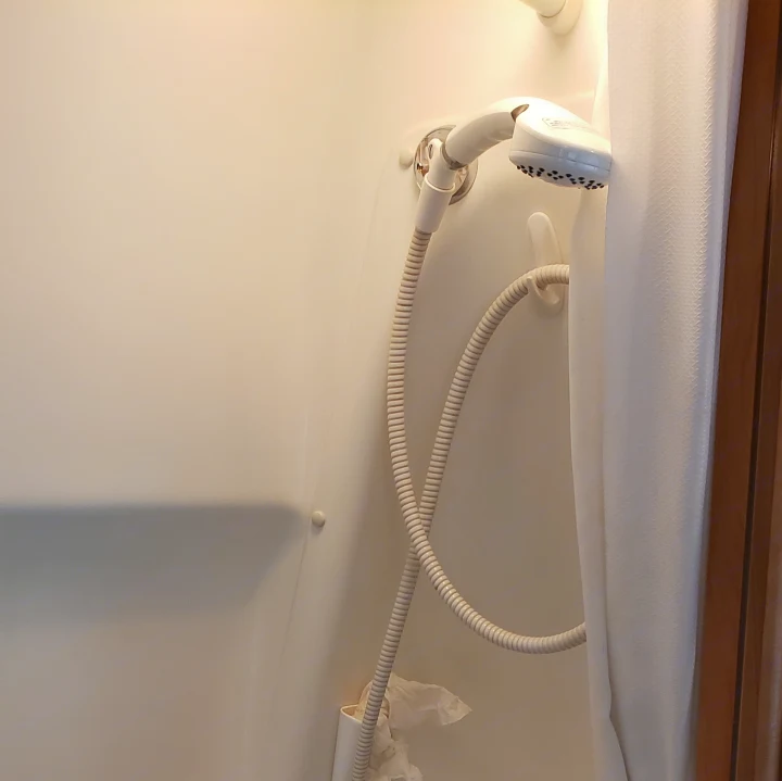 Compact shower in an RV rental, featuring a handheld shower head and hose. Ideal for travel needs.. ERA Era 2010