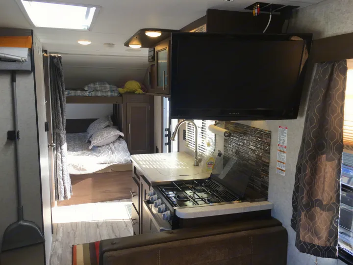Bright RV rental interior features a functional kitchen, entertainment TV, and cozy bunk bed area.. Forest River Cherokee Grey Wolf 2018