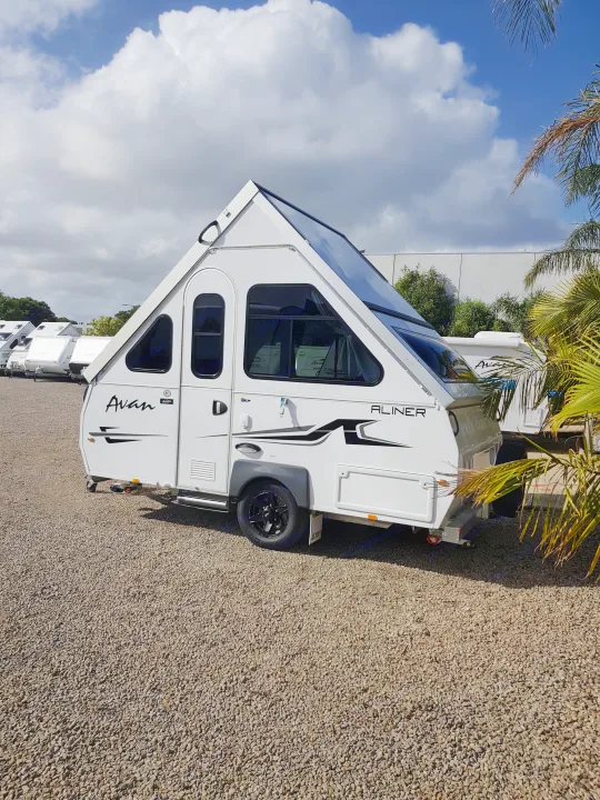 White Avan A-liner A-frame camper, perfect for your next RV rental, parked on gravel with other units visible.. Avan Aliner Camper 2022