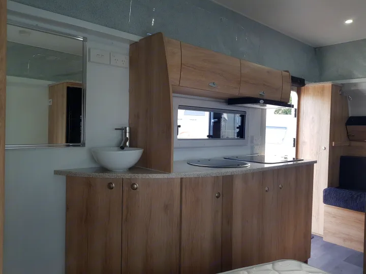This RV rental's well-designed kitchen features a modern sink, covered cooktop, and ample wood cabinets for compact living.. Avan Aspire 499 Bunk 2020