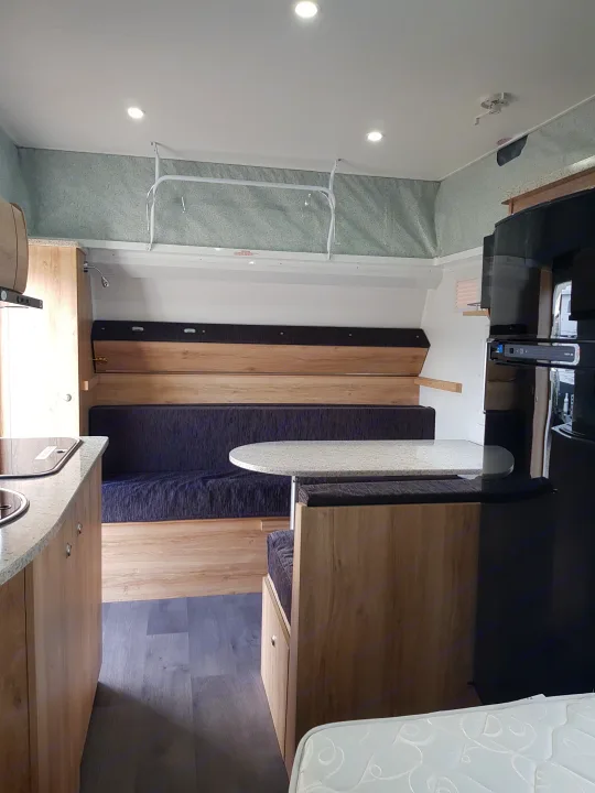 Spacious RV rental interior featuring a dinette, compact kitchen with sink, and a convertible bed area.. Avan Aspire 499 Bunk 2020