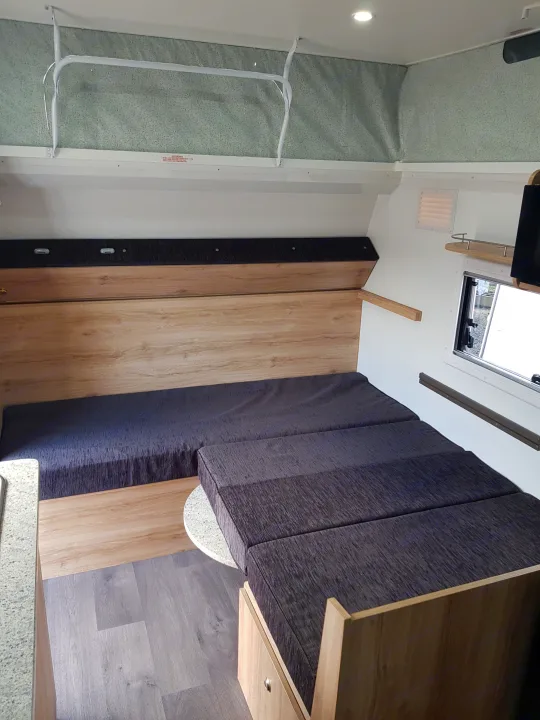 RV rental's inviting interior features a convertible bed/seating area, light wood finishes, and a pop-top roof.. Avan Aspire 499 Bunk 2020