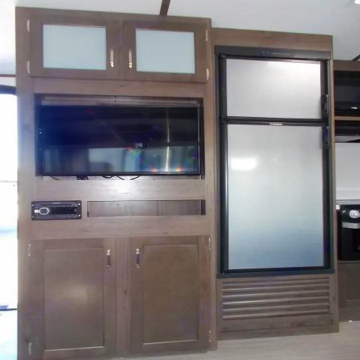 RV rental interior: Built-in entertainment unit with TV, stereo, cabinets, and compact refrigerator for your travels.. Keystone Passport 2020