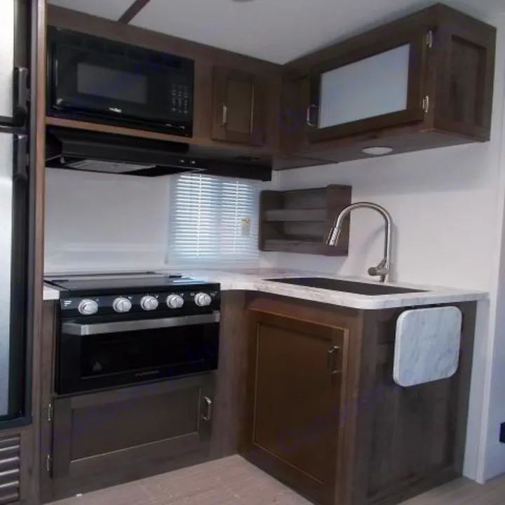 RV rental kitchen: modern interior with microwave, stove, oven, sink, and cabinets for travel comfort.. Keystone Passport 2020
