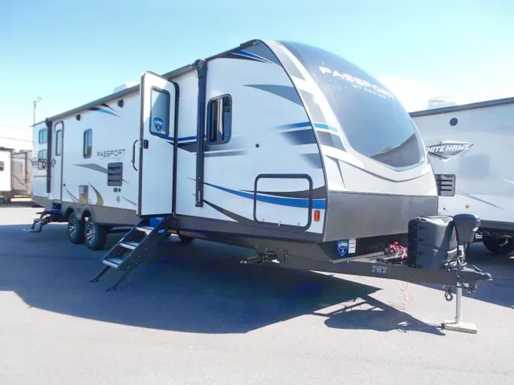 This sleek white "Passport" RV rental travel trailer with an open side door and large front window is ready for camping adventures.. Keystone Passport 2020
