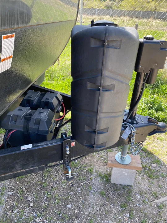 Front of an RV rental trailer, showcasing the propane tank system, dual batteries, and hitch with a jack for stability.. Forest River Sandstorm 2017