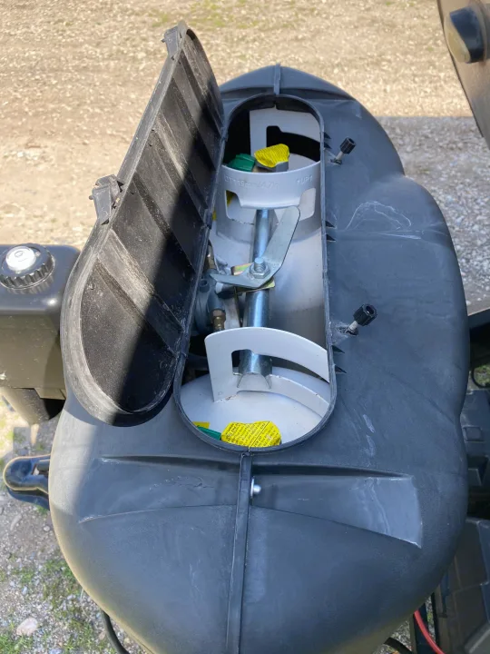 Open propane tank cover on an **rv rental**, revealing two white propane tanks with a regulator for gas supply.. Forest River Sandstorm 2017