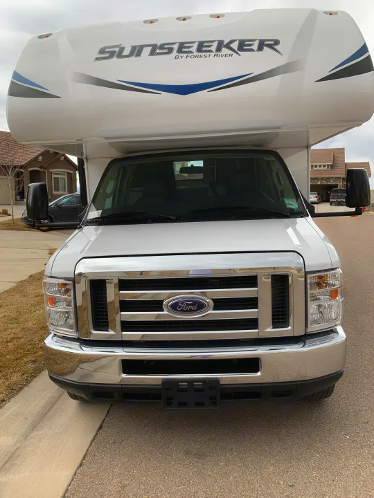 Front view of a white Ford Sunseeker RV, ideal for an RV rental, parked on a residential street.. Forest River Sunseeker 2019