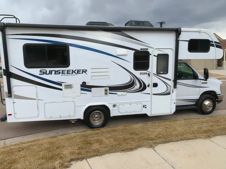 White Forest River Sunseeker RV rental, parked on street. Full side view of this travel-ready motorhome.. Forest River Sunseeker 2019