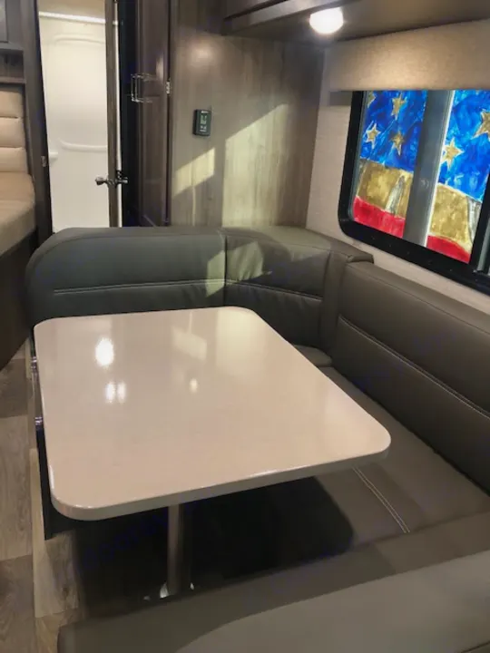 Experience RV rental comfort: a clean dining area with a table, padded benches, and a patriotic skylight view.. Winnebago Minnie Winnie 2020