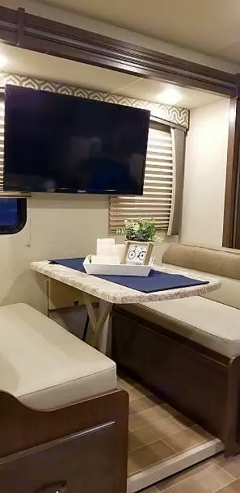 This RV rental offers a comfortable dining booth with a table, light cushions, and a mounted TV overhead, ideal for relaxing meals.. Other Other 2020