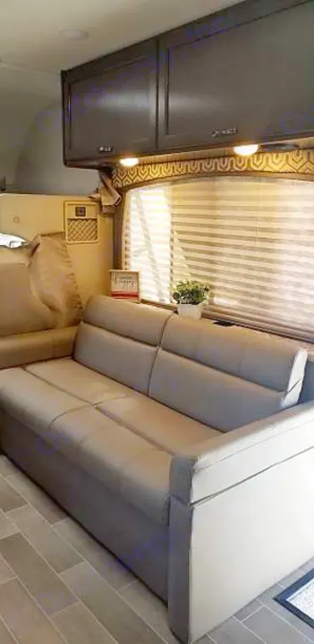 Modern RV rental interior with a comfortable couch, overhead cabinets, and window blinds.. Other Other 2020