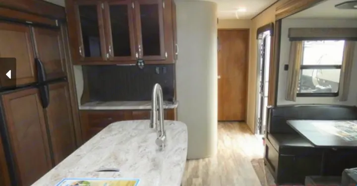 Spacious RV rental interior featuring a well-equipped kitchen with an island sink, refrigerator, and a comfortable dining booth.. Grand Design Reflection 2019