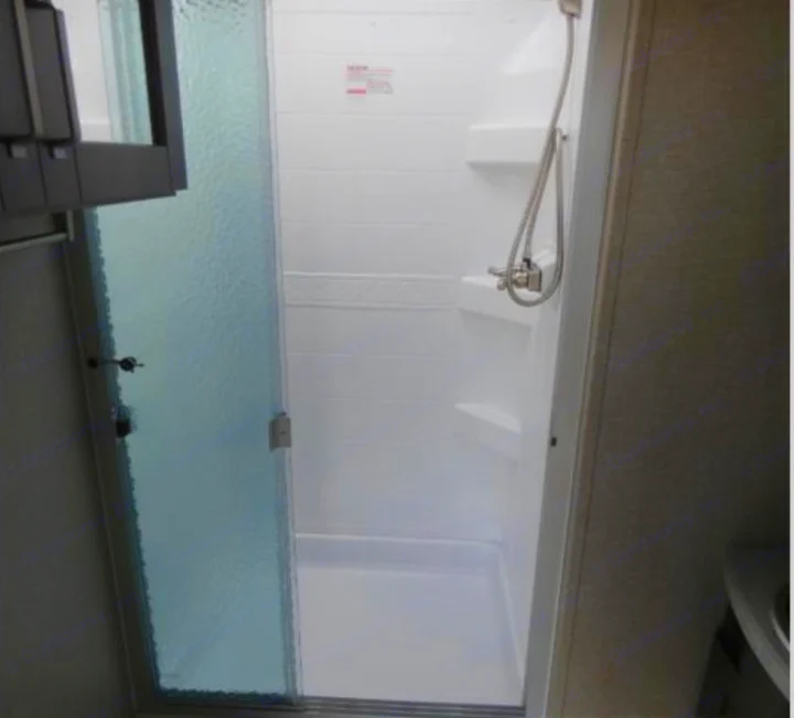 Modern RV rental interior: a bright, compact shower stall with a textured glass door and handheld sprayer.. Grand Design Reflection 2019