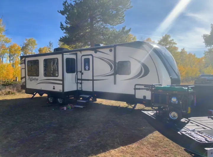 Spacious RV rental parked at a sunny autumn campsite with a generator nearby. Perfect for outdoor adventures.. Grand Design Reflection 2019