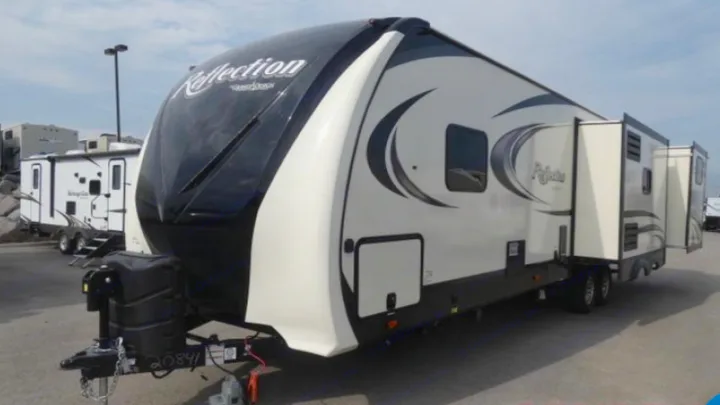 White and black Reflection fifth wheel RV rental with extended slide-outs, parked in a lot.. Grand Design Reflection 2019