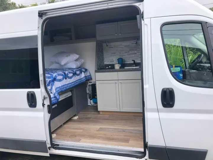 Bright rv rental camper van interior: cozy bed, compact kitchen, Dometic cooler. Ready for your next adventure.. Dodge Sprinter 2500 170ext 2015