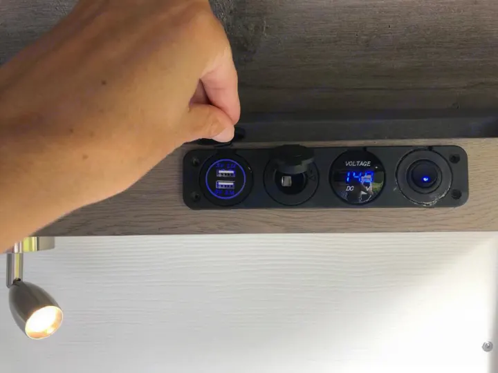 Hand on an RV rental's interior power panel, showing USB charging, a 12V socket, and a 14.8V DC voltage display.. Dodge Sprinter 2500 170ext 2015