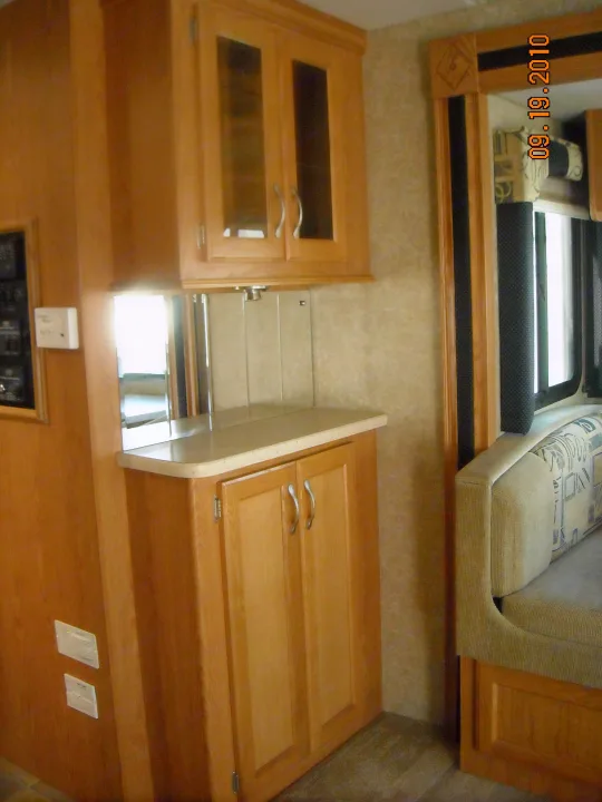 Spacious RV rental interior featuring light wood cabinetry, mirrors above the counter, and comfortable dinette seating.. Thor Motor Coach Hurricane 34N 2006