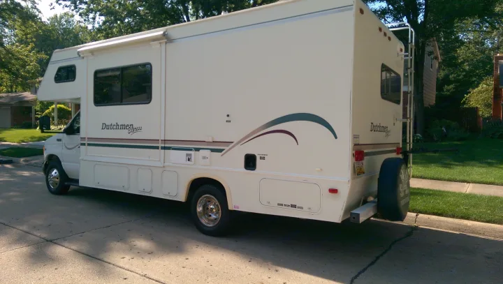 Side view of a white Dutchmen Express RV rental, a Class C motorhome parked on a street.. Dutchmen Other 2001